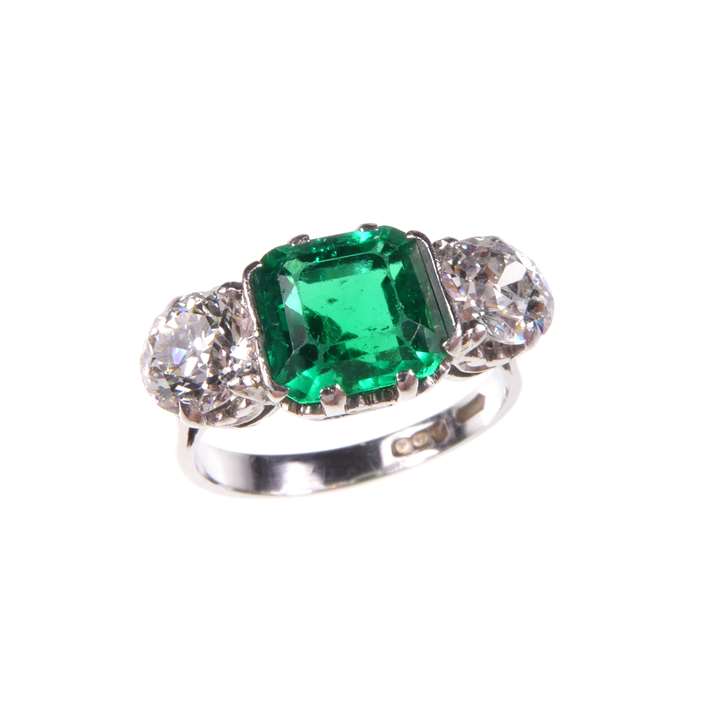 Emerald and diamond three stone ring, the octagonal step cut emerald between old round brilliant cut diamonds